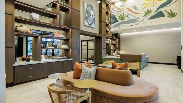 A modern interior with a sofa, chairs, a bar area, and a reception desk. - Landing | Spectacular 1BD, Gym (Austin)