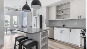 A modern kitchen with a central island, pendant lights, and a view to the outside. - Landing | Spectacular 1BD, Gym (Austin)