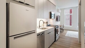 Een moderne keuken met een inbouwvaatwasser, roestvrijstalen apparatuur en een raam met rode luiken.