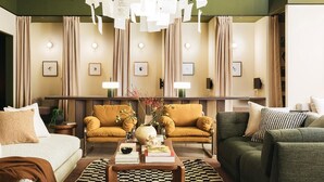Een moderne woonkamer met een bank, fauteuils, een salontafel en een decoratieve vaas.