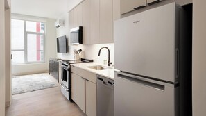 Eine moderne Küche mit eingebautem Geschirrspüler, einem Edelstahl-Kühlschrank und einem Fenster mit Jalousien.