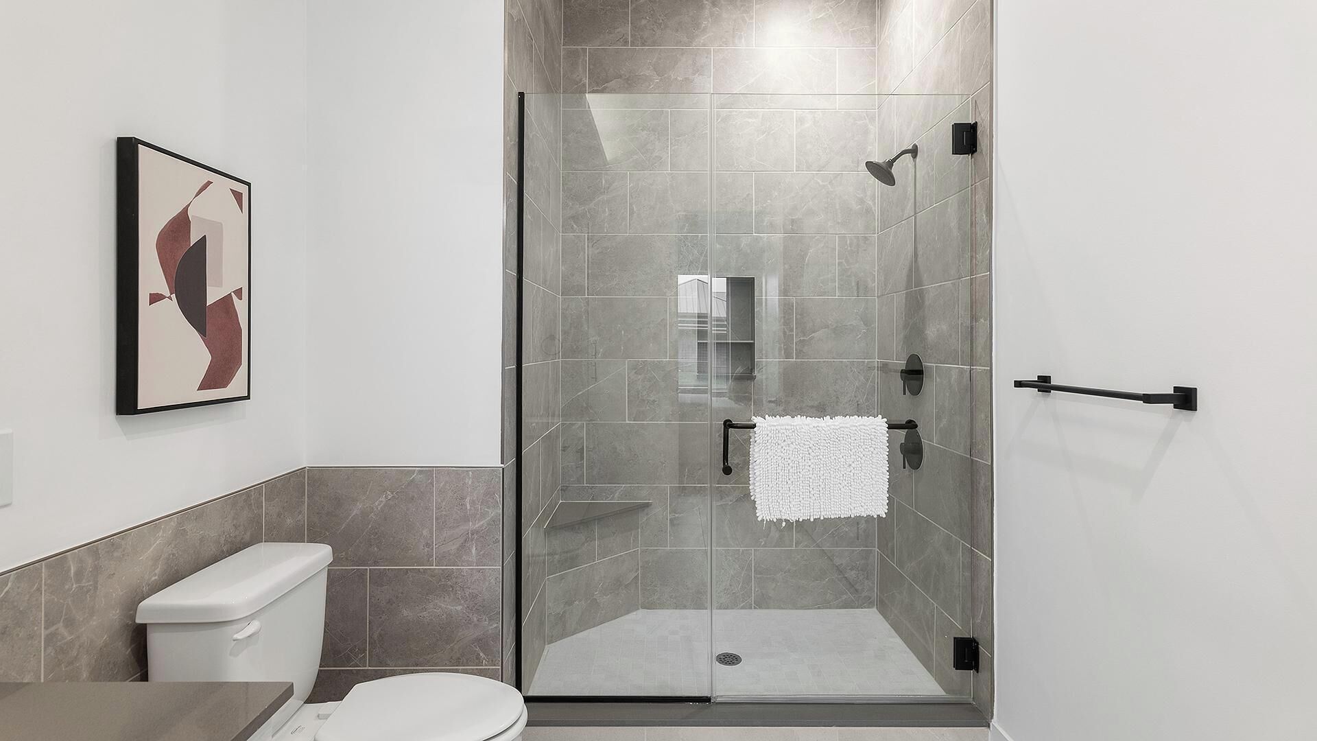 A modern bathroom with a glass shower enclosure, a toilet, and a sink.