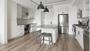 A modern kitchen with a central island, stainless steel appliances, and a minimalist design. - Landing | Stylish 1BD, Gym (Austin)