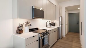 Una cocina moderna con armarios blancos, una estufa de acero inoxidable, horno empotrado y refrigerador.
