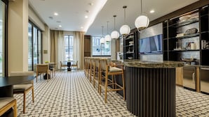 Moderni hotellihuone, jossa on ruokailutila, baari ja suuri ikkuna, jossa on verhot.