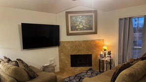 Ein Wohnzimmer mit Flachbildfernseher, Kamin und zwei Sofas.