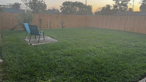 Ein Garten mit Holzzaun, Rasen und blauem Stuhl.