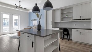 A modern kitchen with a central island, pendant lights, and light wood cabinetry. - Landing | Beautiful 1BD, Gym (Austin)