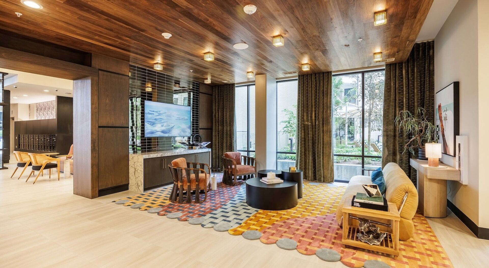 A modern living room with a wooden ceiling, a TV, a bar area, and large windows.
