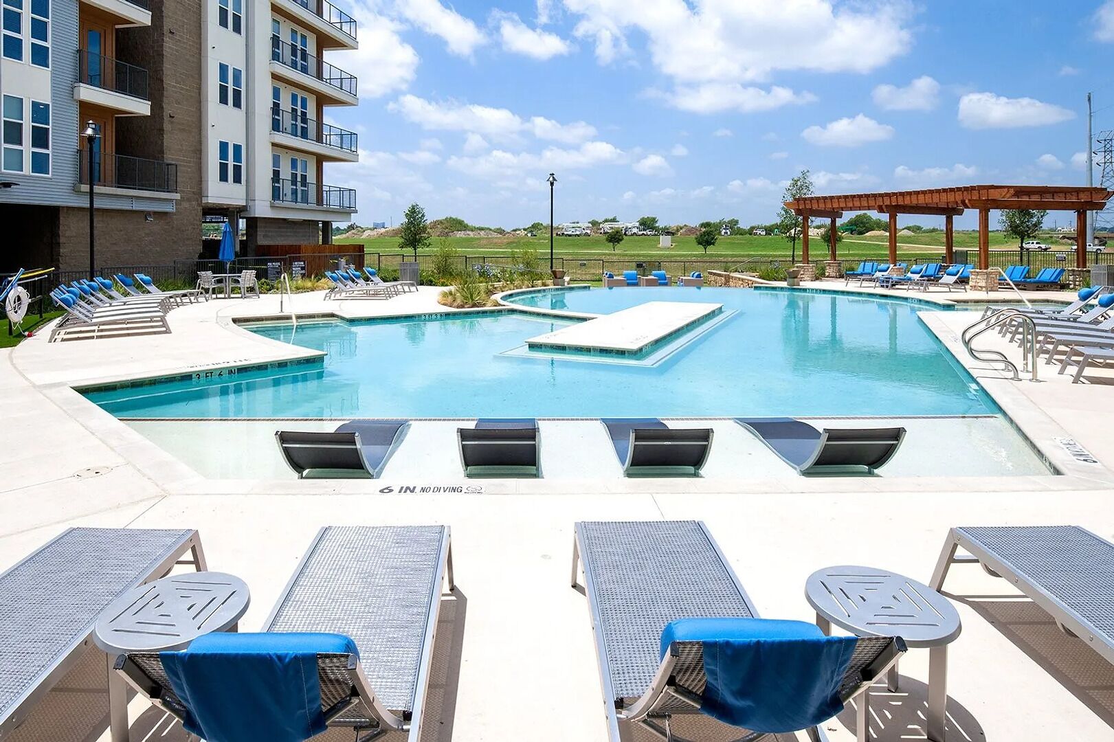 A pool area with multiple swimming pools, lounge chairs, and a covered seating area.