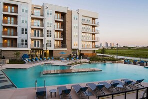 A modern hotel with a pool area, multiple balconies, and a view of the city skyline. - Landing | Modern 1BD in Downtown Fort Worth (Fort Worth)