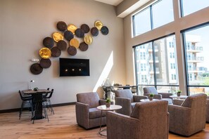 A modern living room with a flat-screen TV, a dining area, and large windows offering a view of the cityscape. - Landing | Modern 1BD in Downtown Fort Worth (Fort Worth)