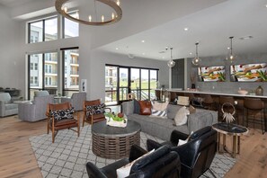 A spacious living room with a large sofa, a coffee table, and a dining area with bar stools. - Landing | Incredible 2BD in Downtown Fort Worth (Fort Worth)