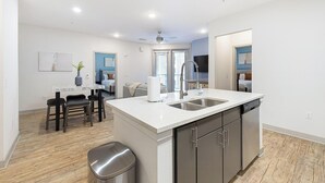 A modern kitchen with a central island, stainless steel appliances, and a dining area with a table and chairs. - Landing | Incredible 2BD in Downtown Fort Worth (Fort Worth)