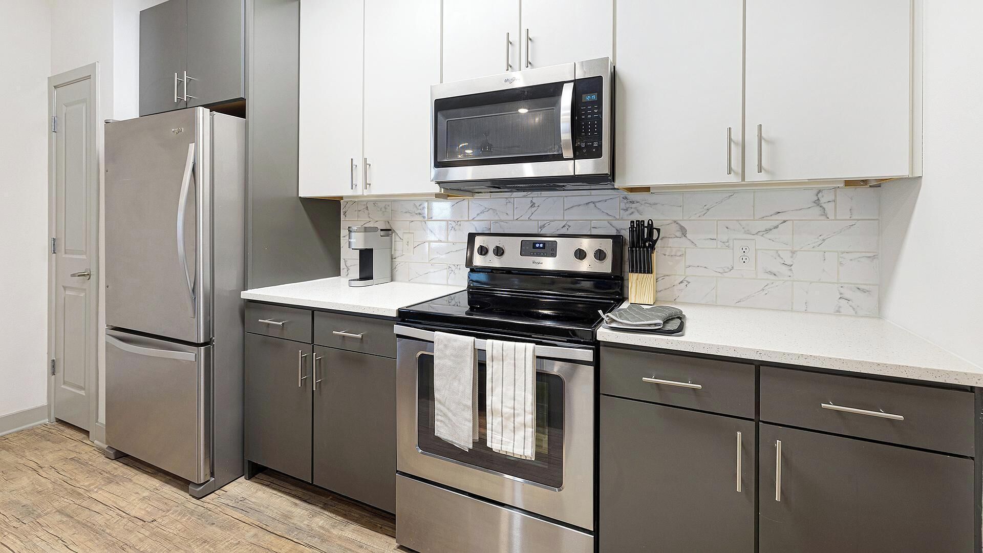 A kitchen with stainless steel appliances, marble backsplash, and modern cabinetry.