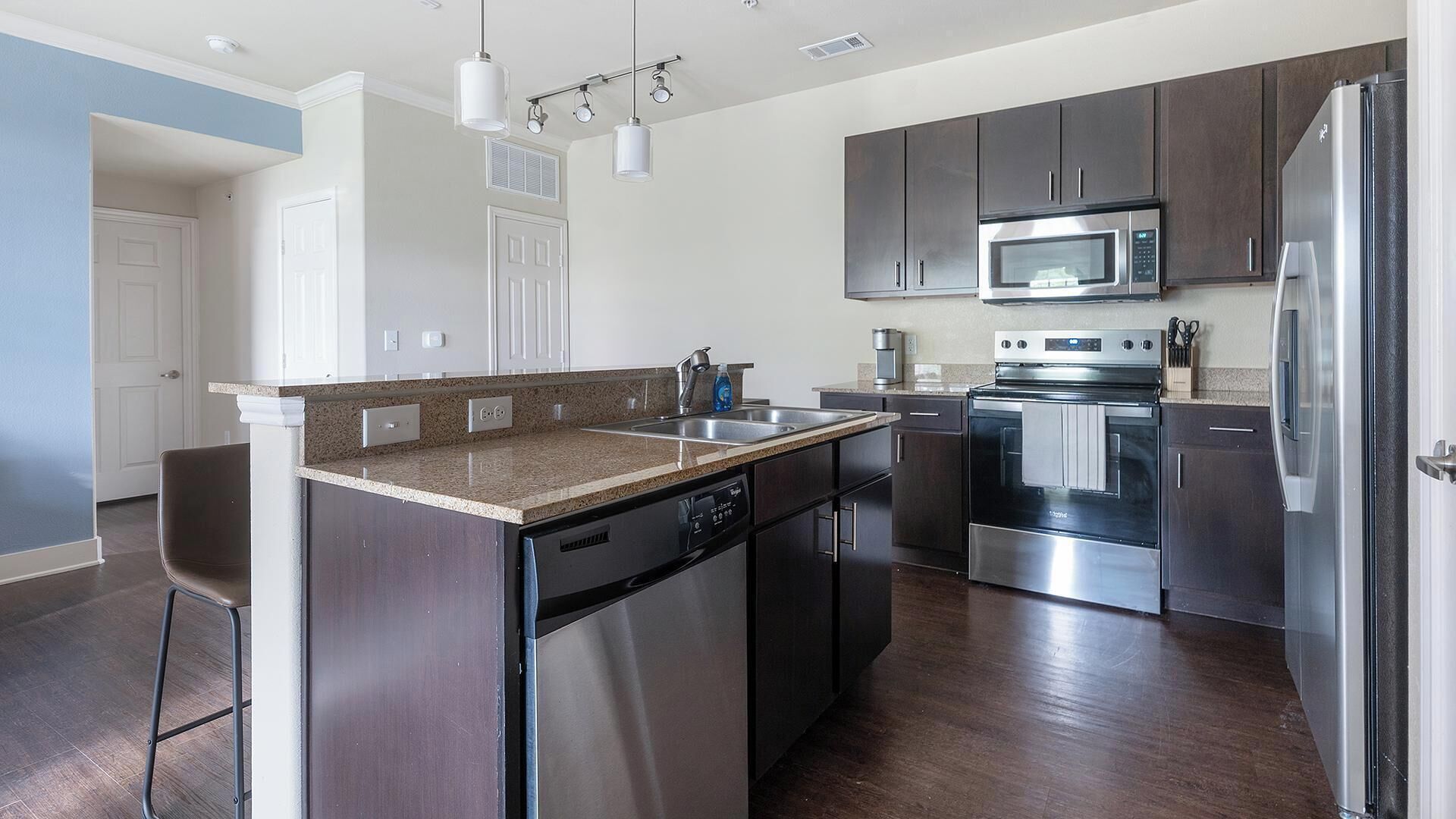 A modern kitchen with stainless steel appliances, a granite countertop, and dark cabinetry.