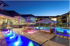 Ein Poolbereich mit Wasserspiel, Liegestühlen und Sonnenschirmen.