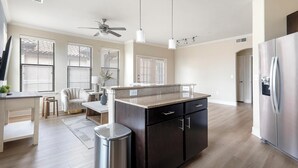 Una cucina moderna con isola centrale, mobili scuri, elettrodomestici in acciaio inossidabile e una ventola a soffitto.