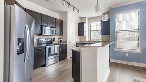 Una cucina moderna con elettrodomestici in acciaio inossidabile, un forno a microonde e un fornello.