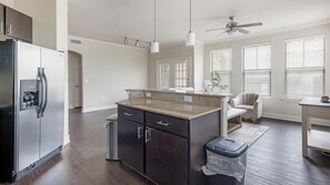 A modern kitchen with a refrigerator, a sink, and a countertop. - Landing | Modern 2BD, Gym (Austin)