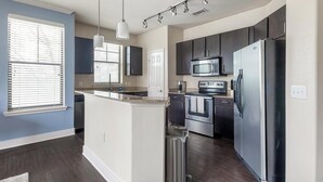 Une cuisine moderne avec des meubles de couleur sombre, des appareils électroménagers en acier inoxydable et un îlot central.