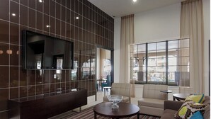 Un salon moderne doté d’un téléviseur à écran plat, d’un canapé, d’une table basse et d’une grande fenêtre offrant une vue dégagée.