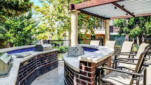 Une terrasse extérieure équipée d’un barbecue, d’un bain à remous et de meubles de jardin.