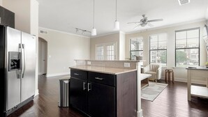 A modern kitchen with a stainless steel refrigerator, a granite countertop, and a ceiling fan. - Landing | Amazing 2BD, Gym (Austin)