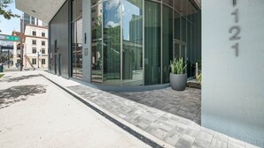 Un edificio moderno con amplios ventanales de vidrio, un cartel de calle que indica 'NE 1 AV' y una planta en maceta en el exterior.