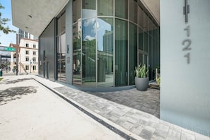 A modern building with large glass windows, a visible street sign reading 'NE 1 AV,' and a potted plant outside. - Downtown Miami Retreat 406 | City Views & Pool (Miami)