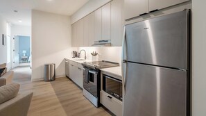 A modern kitchen with stainless steel appliances, a dishwasher, and a countertop with a sink and utensils. - Landing | Spectacular 1BD in Lincoln Park (Chicago)
