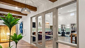 A modern interior with a wooden floor, a dining area with chairs, and a kitchen visible through glass doors. - Landing | Amazing 1BD, Clubhouse, Gym (Goodyear)