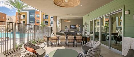 Un patio techado al aire libre con piscina, comedor y zona de estar.
