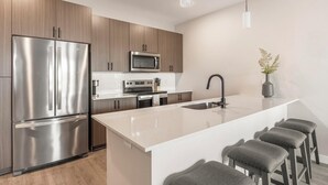 Una cucina moderna con elettrodomestici in acciaio inossidabile, mobili in legno, un'isola centrale con sgabelli da bar e un design minimalista.