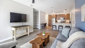 Ein modernes Wohnzimmer mit Flachbildfernseher, einer Couch, einem Couchtisch und einem Essbereich mit Tisch und Stühlen.