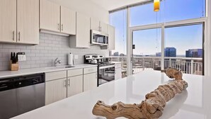 Eine moderne Küche mit weißen Schränken, einer großen Kochinsel und Blick auf die Stadt durch die Fenster.