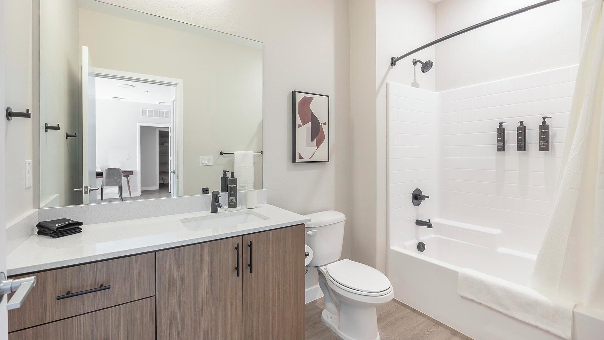 A modern bathroom with a white sink, vanity, toilet, and a walk-in shower.