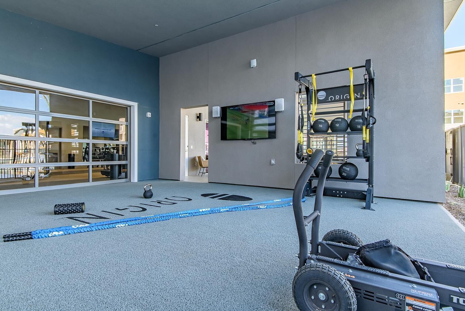 Une salle de sport équipée d’un espace dédié à la musculation, d’un tapis de course et d’une grande fenêtre.