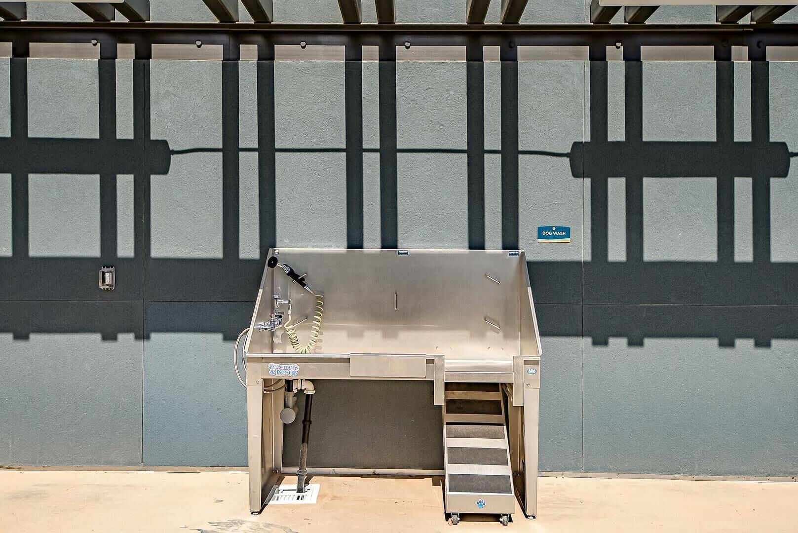 A portable dog wash station with a ladder, a hose, and a sign indicating its purpose.