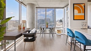 Un espace de bureau moderne doté d’une grande fenêtre, d’une table avec des chaises, d’un coin bar et offrant une vue sur le paysage urbain.
