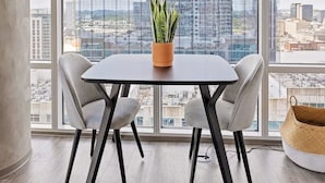 Un espace de bureau moderne doté d’une grande fenêtre, d’une table avec deux chaises, d’une plante en pot et d’un panier en osier.