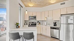 Eine moderne Küche mit Edelstahlgeräten, einer Bar mit zwei Sesseln und Blick auf die Stadt.
