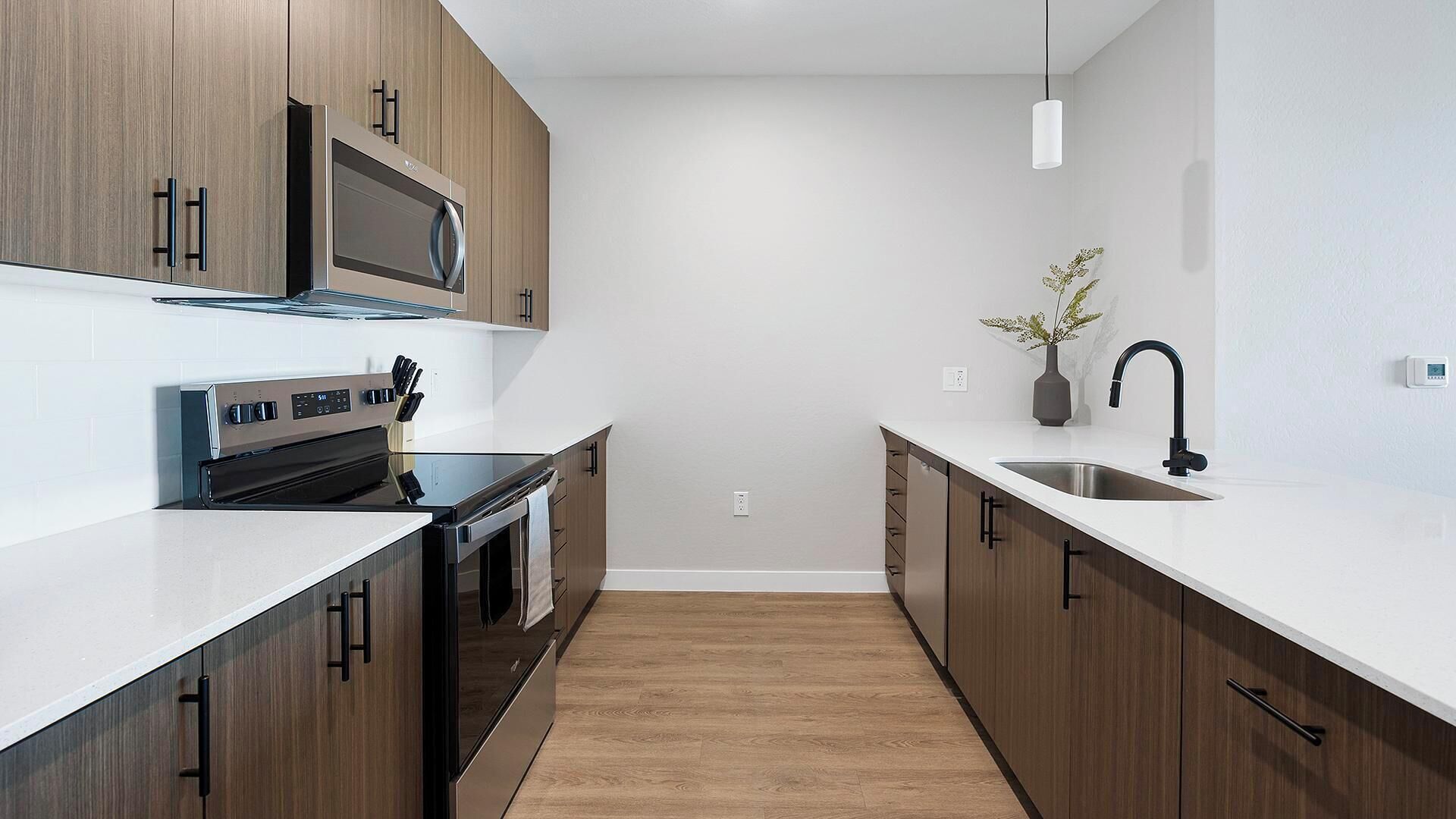 A modern kitchen with wooden cabinets, a stainless steel sink, and a built-in oven.