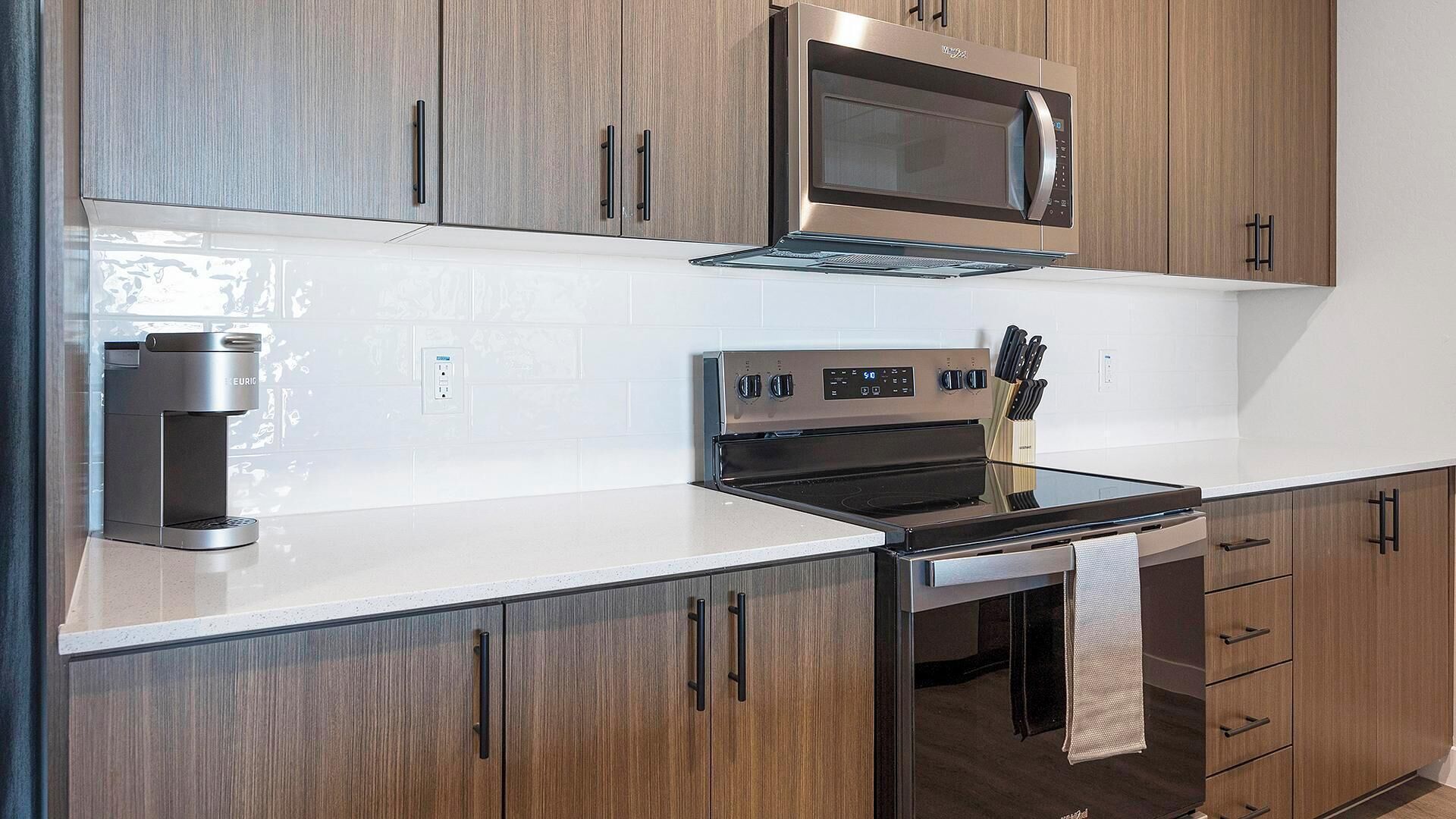 A kitchen with wooden cabinets, a microwave, a coffee maker, and a stove.