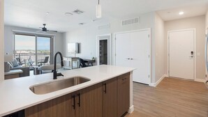 Une cuisine moderne dotée d’un grand îlot central, d’un coin repas offrant une vue agréable et d’un dressing.