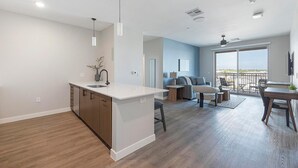 Une cuisine moderne dotée d’un îlot central, d’un coin repas avec une table et des chaises, et d’un balcon offrant une vue agréable.
