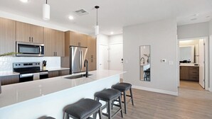 A modern kitchen with stainless steel appliances, a large island with bar stools, and a minimalist design.