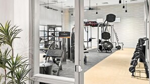 A modern gym with exercise equipment, a 'FITNESS' sign, and a large window.