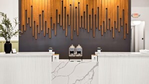 A reception desk with a modern design, featuring a wooden wall panel and a marble countertop. - Landing | Stylish 1BD, Clubhouse, Pool (Goodyear)