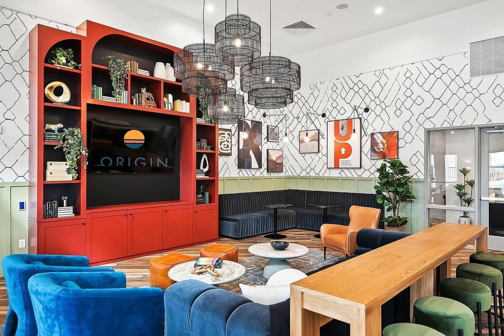 Un salon moderne avec un meuble de rangement rouge pour l’équipement audiovisuel, un grand téléviseur, un canapé d’angle noir, une table basse en bois et un lustre original.